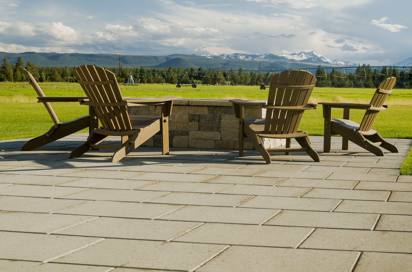 Patio photo of two wooden chairs next to a fire pit overlooking mountains and fields in Sisters, Oregon