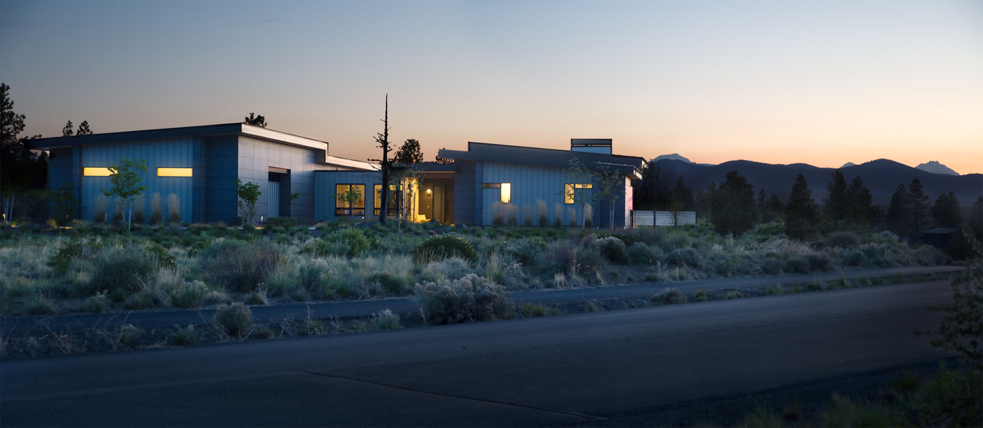 Sunset view of home with interior lighting illuminating inside